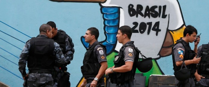 Riot police gather in front of a mural of the mascot for the 2014 World Cup soccer tournament, called Fuleco, near the Maracana stadium ahead of the Confederations Cup soccer final between Brazil and Spain in Rio de Janeiro, Brazil, Sunday, June 30, 2013. (Source: AP Photo/Victor R. Caivano)